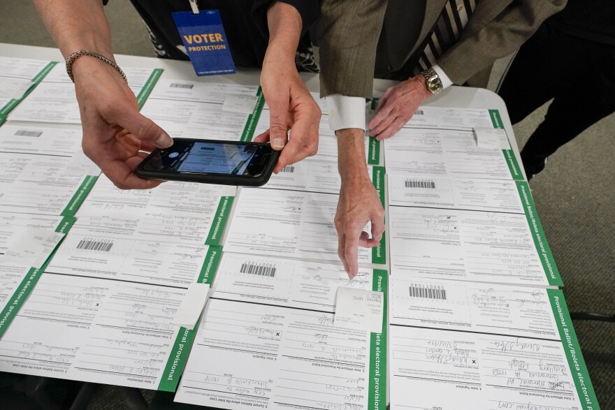 A canvas observer photographs Lehigh County provisional ballots as vote counting in the general election continues, Nov. 6, 2020, in Allentown, Pa. A review by The Associated Press in the six battleground states disputed by former President Trump has found fewer than 475 cases of potential voter fraud, a minuscule number that would have made no difference in the 2020 presidential election. Democrat Joe Biden won Arizona, Georgia, Michigan, Nevada, Pennsylvania and Wisconsin and their 79 Electoral College votes by a combined 311,257 votes out of 25.5 million ballots cast for president.