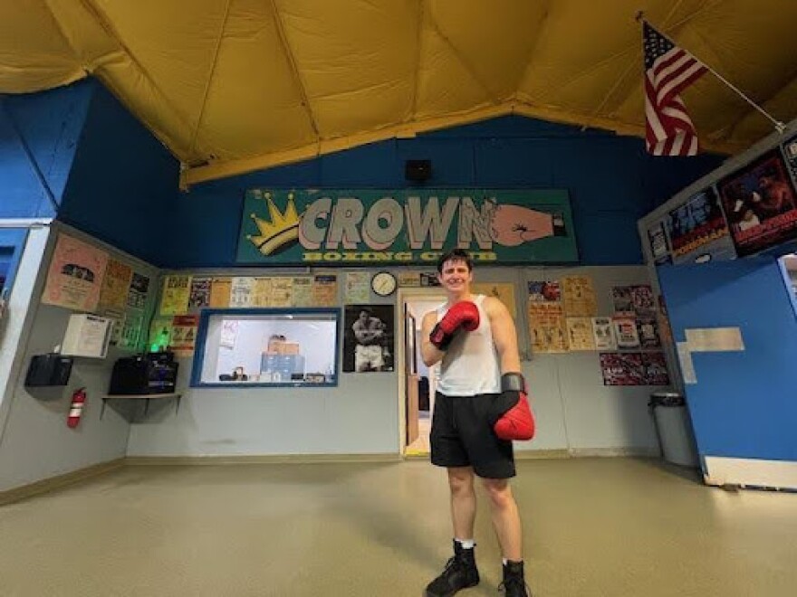 Alex Ziouras poses in front of his team's Crown Boxing Club sign.