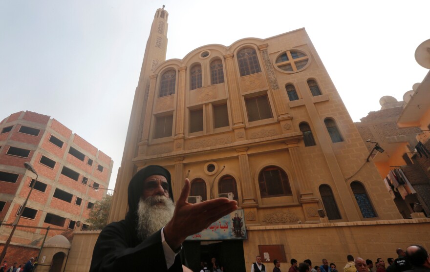 A priest reacts at the site of an attack on a church in Helwan, south of Cairo, on Friday. Officials say the attack killed at least nine people.