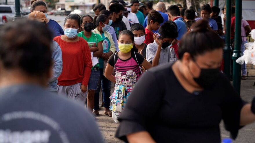 People line up for food donated from a nearby church at a camp for migrants Friday, May 14, 2021, in Reynosa, Mexico. The encampment, like others along Mexico's northern border with the United States, are temporary home for migrants hoping to seek asylum in the United States.