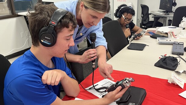 Two students with headphones on learning how to record audio from a microphone