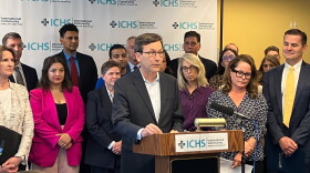 Gov. Bob Ferguson stands at a podium with a crowd behind him. 