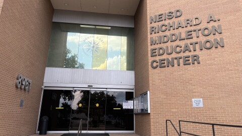 Steps up to the entrance of a brick building with "NEISD Richard A. Middleton Education Center" hanging on the brick.