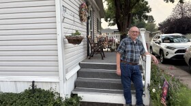 Man stands in front of a white house.