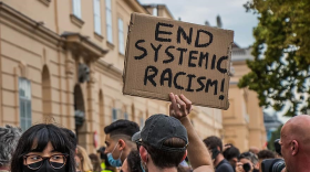 Protester holds up a sign that reads: End systemic racism.
