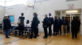 People stand in line at a Detroit polling place during Michigan's March 10 presidential primary. As a result of the pandemic, the state's top election official is sending absentee ballot applications to every registered voter for August and November elections.