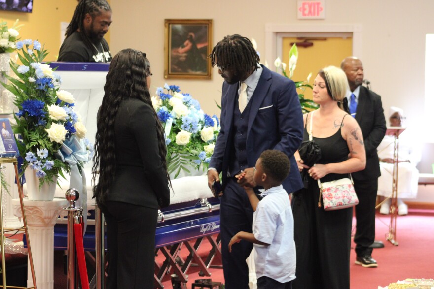 Andre Young and his 5-year-old son view Lloyd Gilmore’s body during his funeral on June 26 at Cornerstone Baptist Church in Sikeston, Missouri. Gilmore died in police custody on June 10. (Cara Anthony/KFF Health News)
