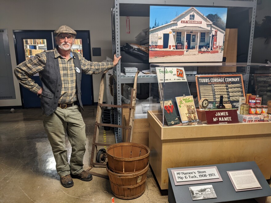 A man standing next to a museum display of historical items from McNamee's General store.