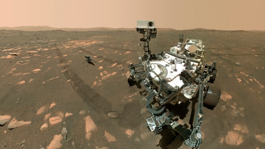 April 6, 2021 image made available by NASA shows the Perseverance Mars rover, foreground, and the Ingenuity helicopter about 13 feet (3.9 meters) behind. 