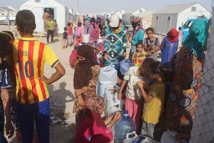 Displaced Iraqis from the Fallujah area wait to fill jerrycans with water at a camp on June 22, 2016.