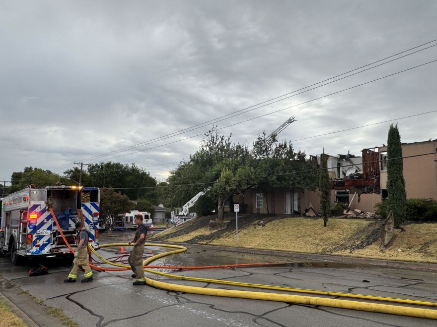 Firefighters stand outside an apartment building in Fort Worth after a three alarm fire that injured five people, including one firefighter.