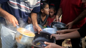 Palestinian children receive food between tents set up for Palestinians seeking refuge on the grounds of a United Nations Relief and Works Agency for Palestine Refugees (UNRWA) centre in Khan Yunis in the southern Gaza Strip on October 24, 2023, amid the ongoing battles between Israel and the Palestinian group Hamas.