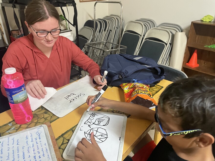Anna Jones (left) smiles after her student successfully read the word "soccer ball" and drew a picture of it. "It's just like, recognizing the small achievements, even if it's just baby steps, we're making some sort of impact. And that's important," she said.