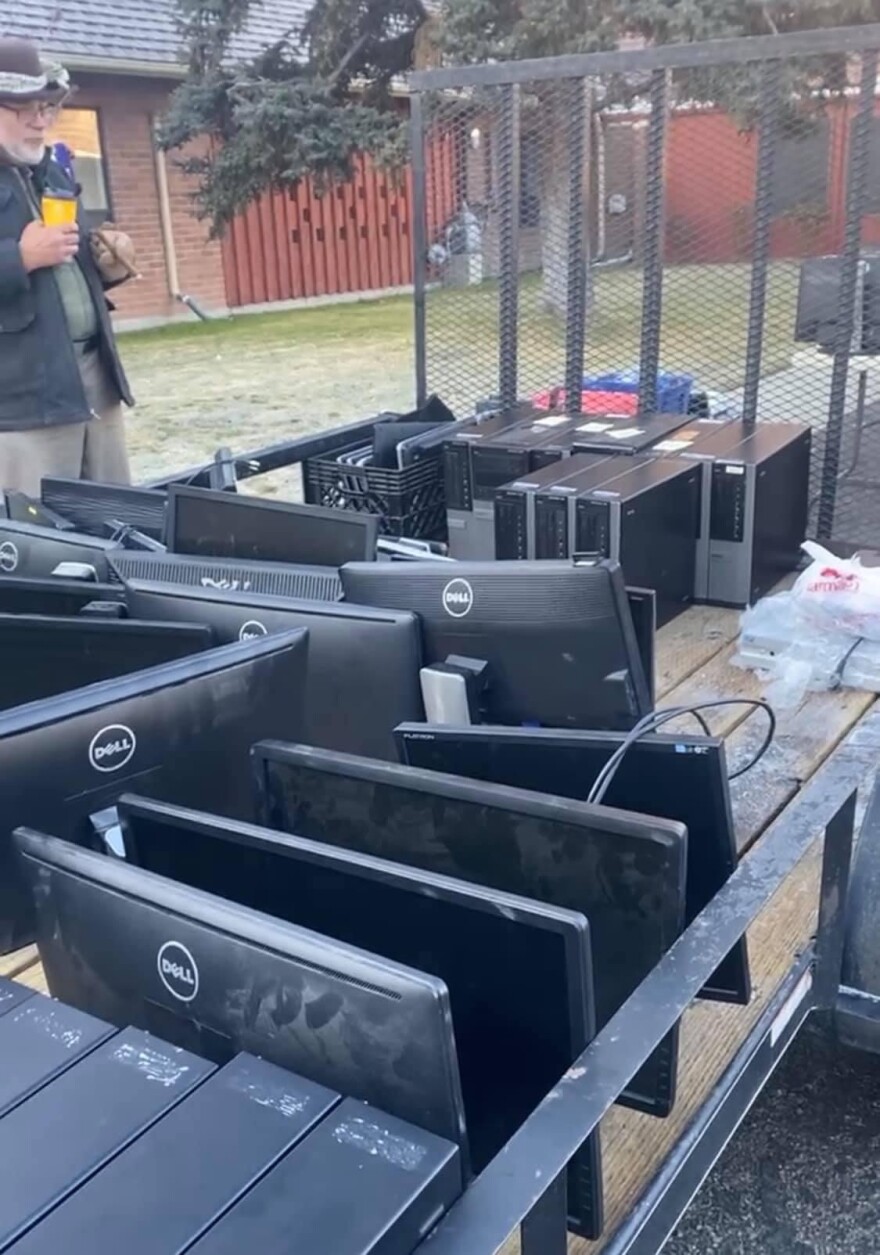An open metal trailer filled with computers and monitors.
