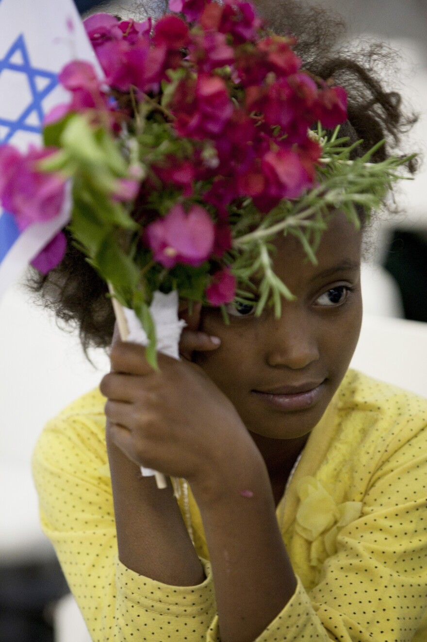 A newly immigrated Ethiopian Jewish girl holds flowers and a flag as she attends a welcoming ceremony at Ben Gurion airport near Tel Aviv, Israel, on Oct. 29, 2012. The Israeli government's program to bring Jews from Ethiopia officially ended this week.