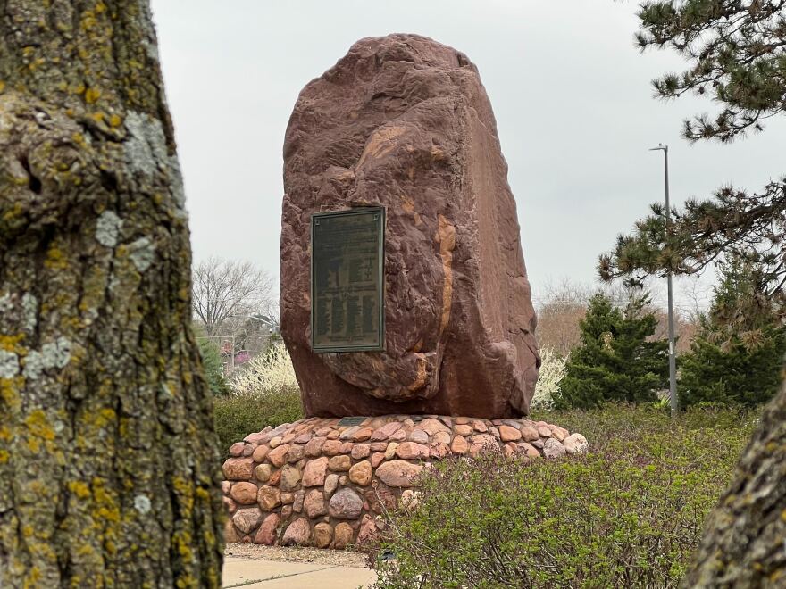 The sacred rock with a plaque on a stone foundation in a city park