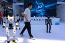 A worker passes by robots from Chinese company Lens at the China International Supply Chain Expo in Beijing on Monday, June 22, 2026. (Ng Han Guan/AP)