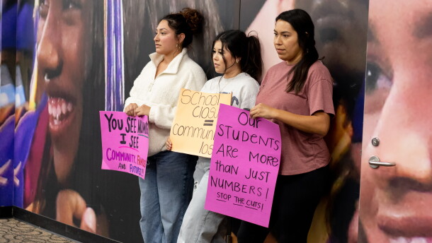 Tulsa community members hold protest signs at the back of the Tulsa Public Schools Board of Education meeting Monday night.