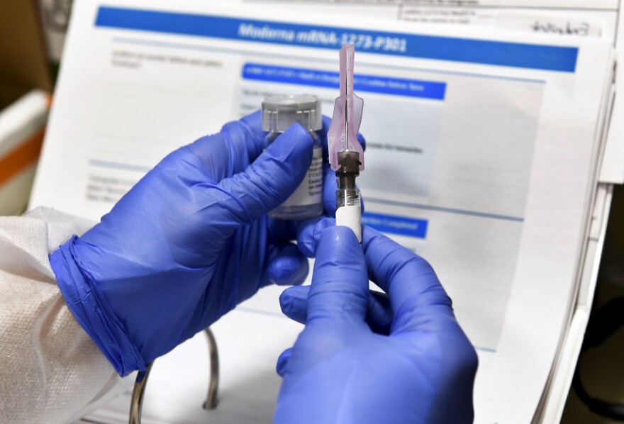 gloved hands holding a syringe