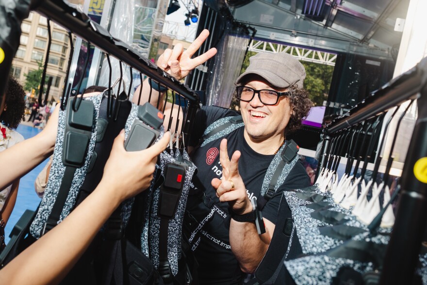 Daniel Belquer of Music: Not Impossible poses for a photo while organizing a rack of haptic suits at the Silent Disco dance party at Lincoln Center, New York City on Saturday, July 1, 2023.