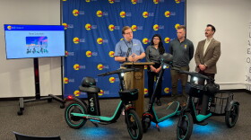 Max Gilles (left) stands with his team as the city announces its transition from Lime to Veo as Grand Rapids' micromobility vendor.