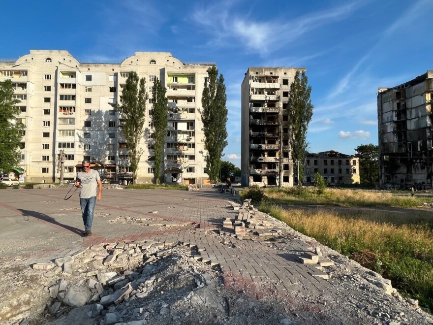 Patrick Patterson walks in front of damaged buildings in Ukraine.