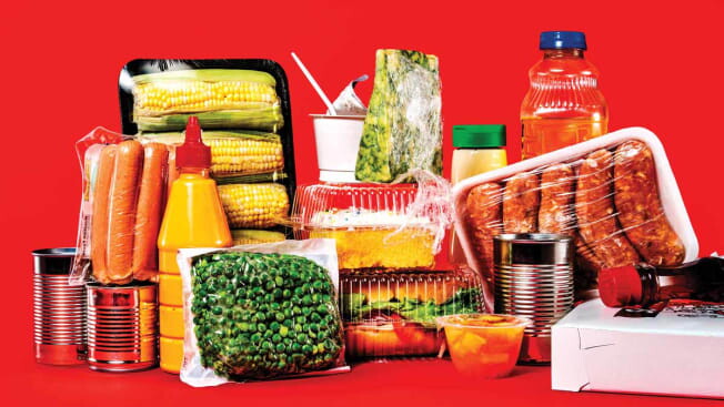 A picture shows plastic wrapped food sitting against a red background.