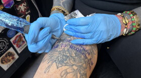 Magic City Tattoo Co. owner Erin Mynes tattoos a Dolly Parton quote onto her thigh. "A loose tongue can lead to broken teeth."