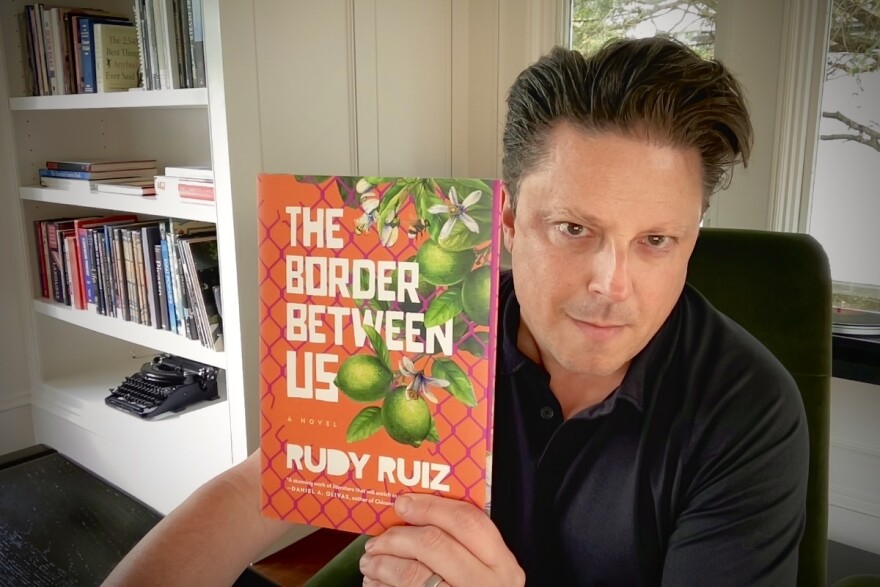 Award-winning author Rudy Ruiz poses with his 2024 novel, "The Border Between Us."