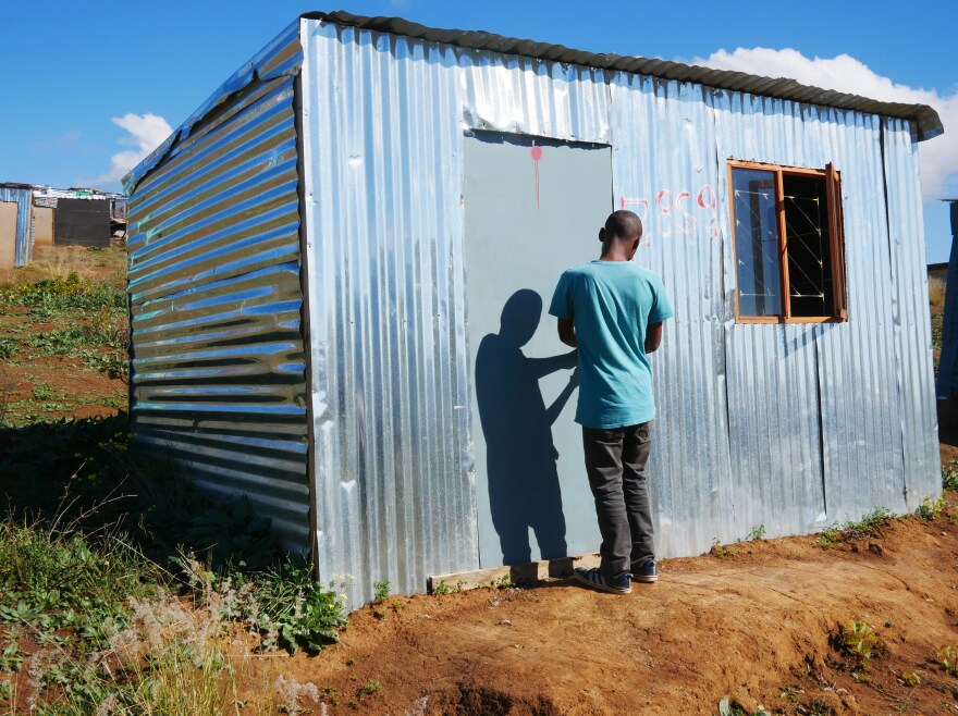 Ayanda stands in the doorway of a shack that he put up on illegally on privately owned farmland in Stellenbosch wine country. He says he grew tired of waiting for housing while living in Kayamandi township.