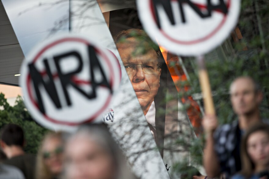 Protesters gather beneath a banner featuring Wayne LaPierre, CEO of the National Rifle Association, during a rally outside the NRA's annual meeting in Dallas in May. When the NRA told doctors to "stay in their lane" instead of weighing in on gun policies, Dr. Joseph Sakran used Twitter to express his outrage.