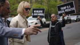 While a protester holds up signs, E. Jean Carroll arrives to federal court in New York on April 27, 2023. (Seth Wenig/AP)
