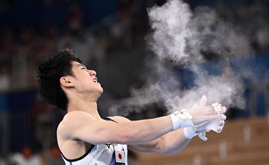 A gymnast claps chalk off his hands during an olympic competition.