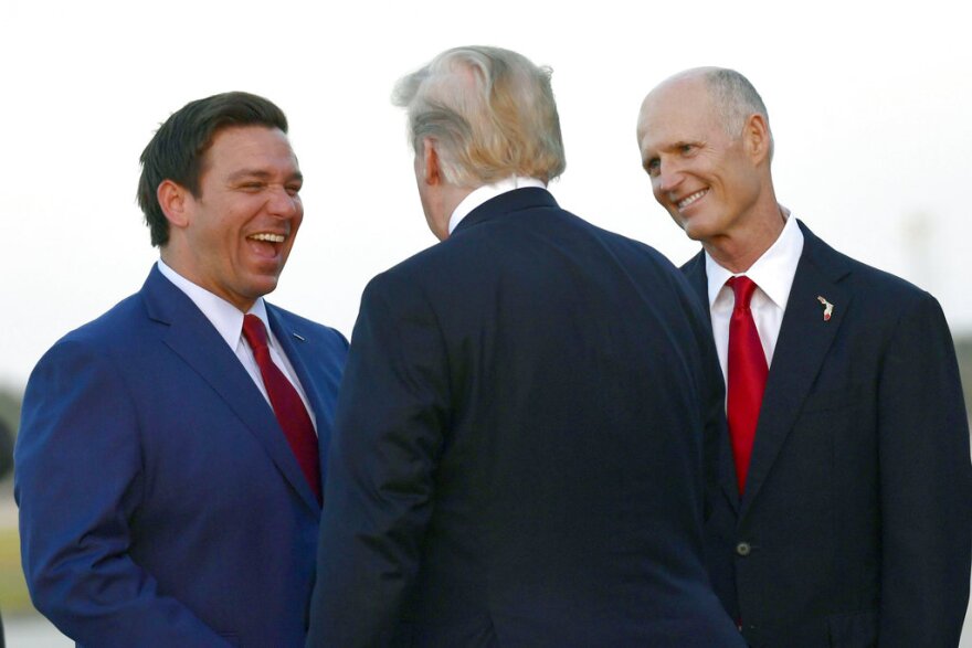 President Donald Trump, center, talks with Republican Gubernatorial candidate Ron DeSantis, left, and Florida Gov. Rick Scott, right, after arriving on Air Force in Fort Myers, Fla. Florida, the site of both a horrific school shooting and a monstrous killer hurricane in the last few months, has become the epicenter of the nation's polarizing political battles. (AP Photo/Susan Walsh, File)