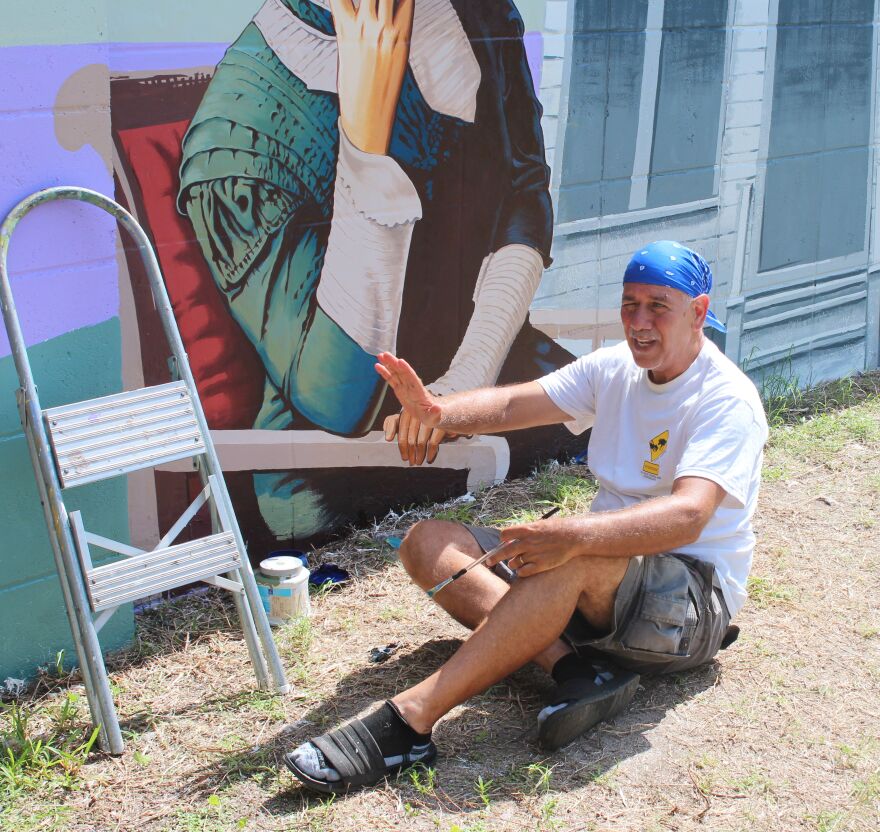 Muralist Roland Ruocco working on Dr. Ella Mae Piper panel of the Buck's Backyard Mural at McCollum Hall.