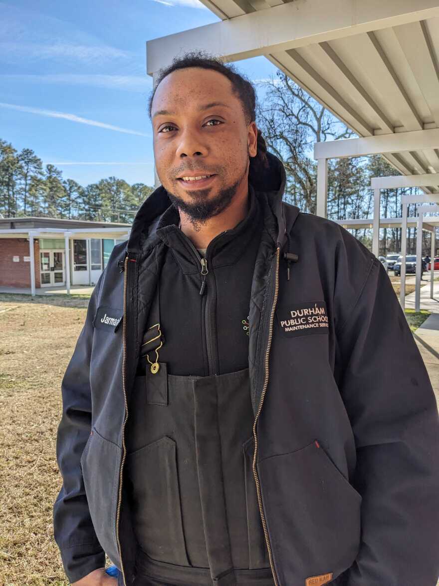 Jarmaal Lawson standing in his work uniform outside a Durham Public Schools' administrative building.