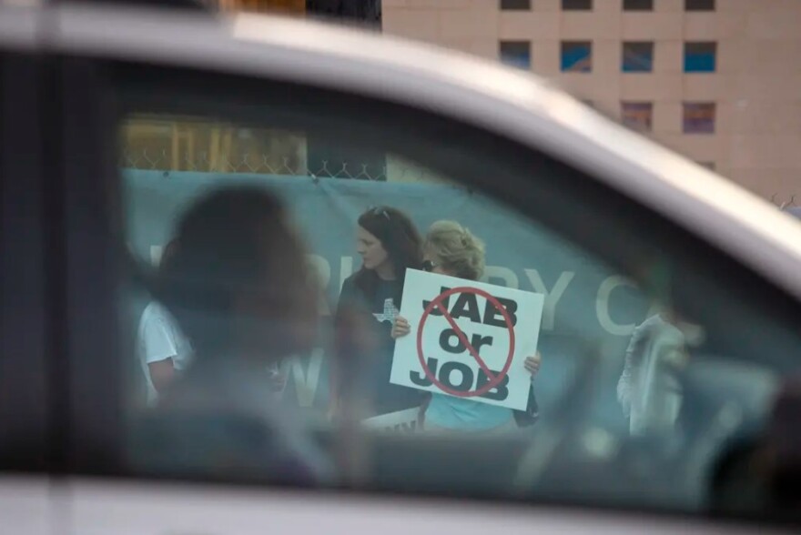 Protesters rallied against Houston Methodist Hospital's COVID-19 vaccine mandate outside the Baytown facility on June 7, 2021. A woman holds a sign that says "No jab or job."