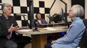 Three people sitting in a radio studio speaking into microphones