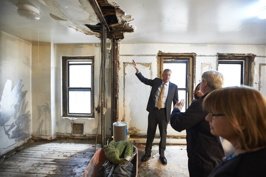 New York City Mayor Bill de Blasio (left) tours an apartment under renovation in the Bronx borough of New York last April. The building is one of four buildings that will lock in a 30-year affordable rental agreement.