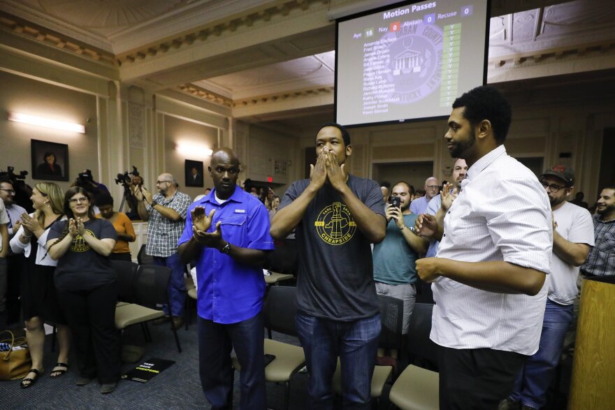 three men celebrating in a room full of people