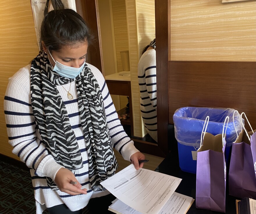 a photo of Sarah Niazi, a case specialist at the International Institute of New England, fills out a questionaire for Afghan evacuees on their first day in Manchester.