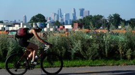 A cyclist passes the Minneapolis skyline along St. Anthony Parkway as smoke from wildfires in Canada and Northern Minnesota sets in, Wednesday, July 15, 2026. (AP Photo/Ellen Schmidt)