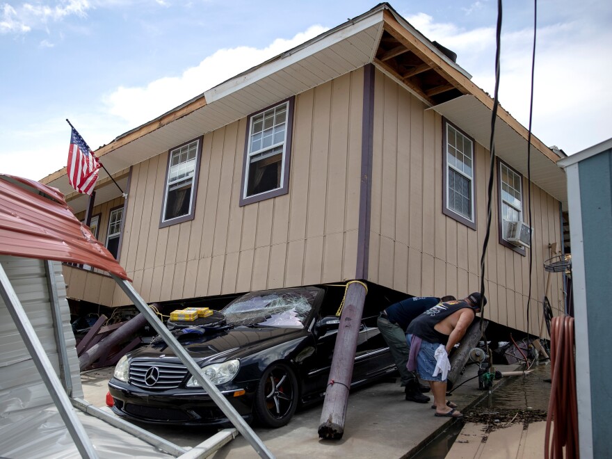 A man checks a broken gas pipe with a firefighter on Monday after Hurricane Ida tore through Bourg, La.