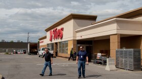 Tops Markets employees walk outside the Tops on Jefferson Ave on May 25. The store is currently surrounded by fencing and has large dumpsters in the parking lot. 