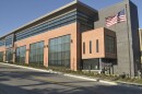 Large brick building with tall windows and an American flag in the foreground