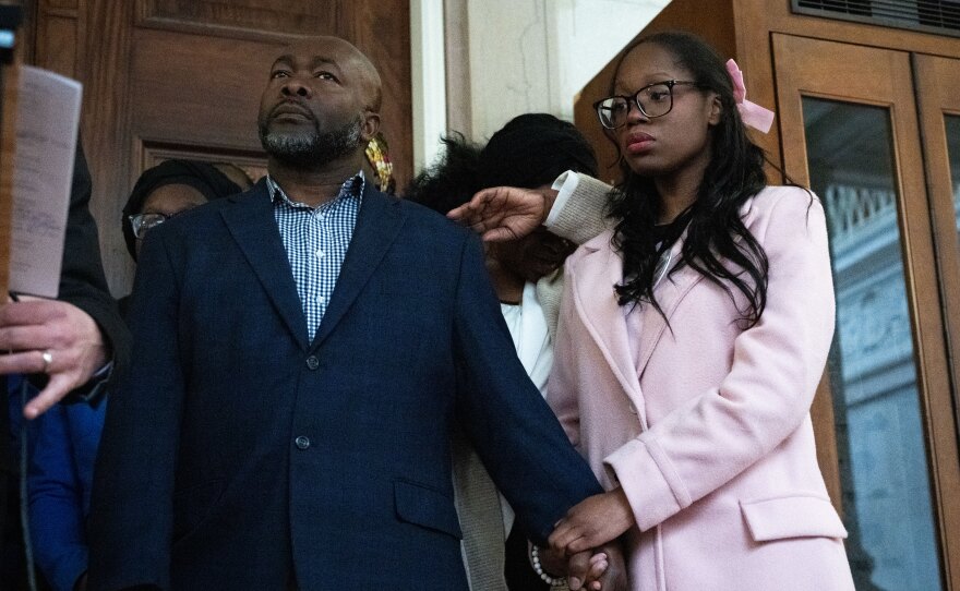 Charles Walker, the brother of Everard Walker, holds the hand of Menon Walker, the daughter of Everard Walker as Everard Walkers mother, Icilda Barton cries behind them inside Hartford Town Hall in Hartford, Connecticut on February 23, 2026.