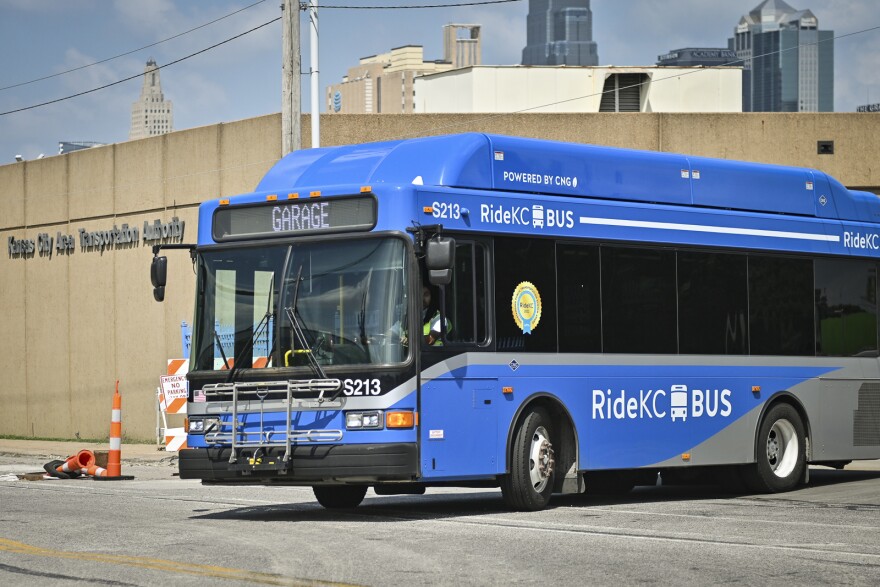 Exterior photo of a blue transit bus entering the street from a parking lot. Behind it is a building with a sigh that reads "Kansas City Area Transportation Authority."