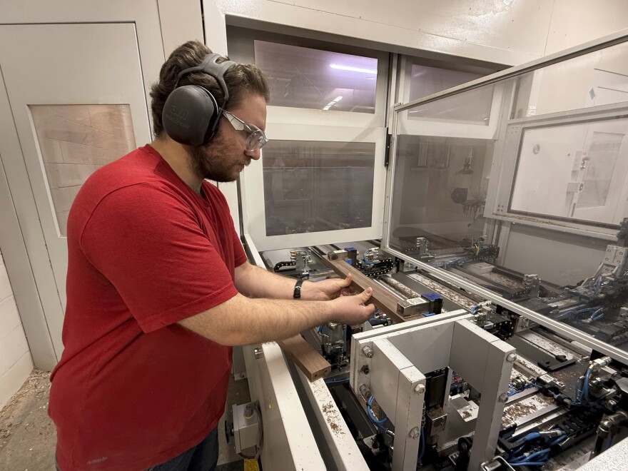 A person works at a machine wearing hearing protection
