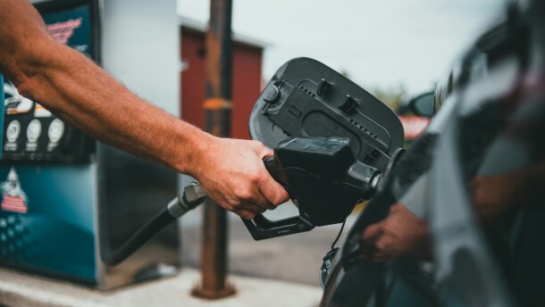 A person pumps gas into a vehicle at a gas station.