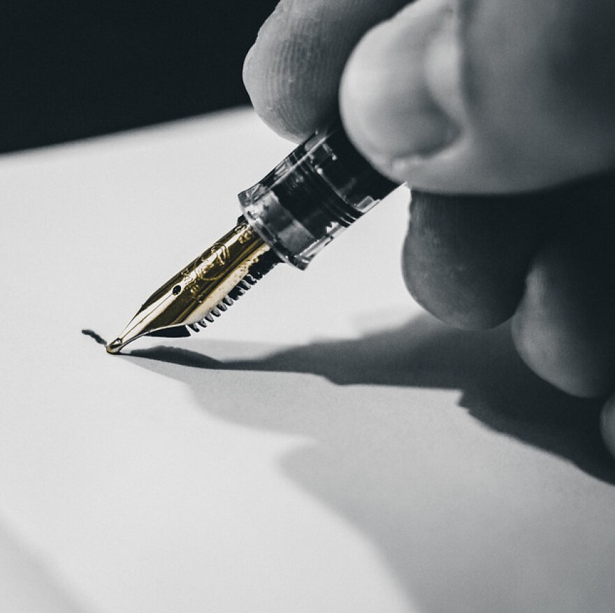 A hand holding a pen on paper.